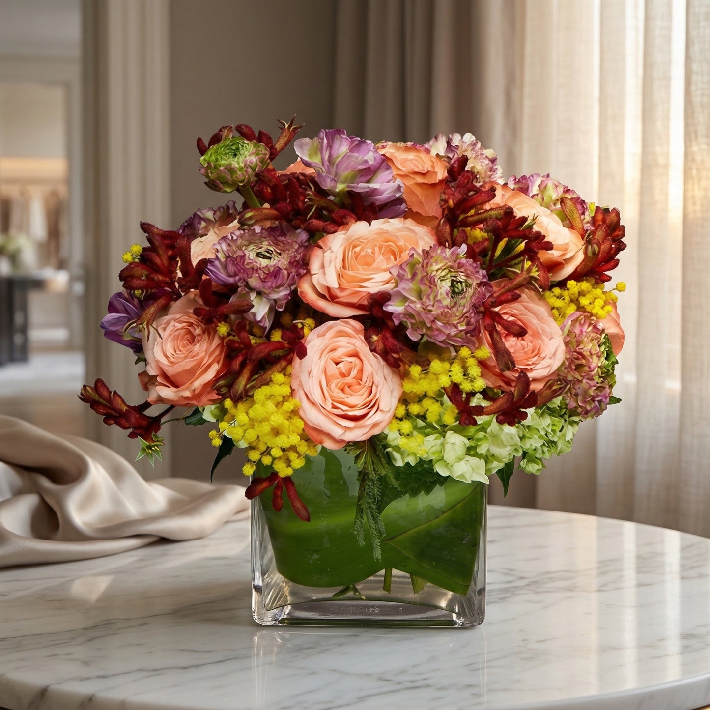 Peach roses, purple ranunculus, and yellow mimosa in a square glass vase - TJ Flowers NYC