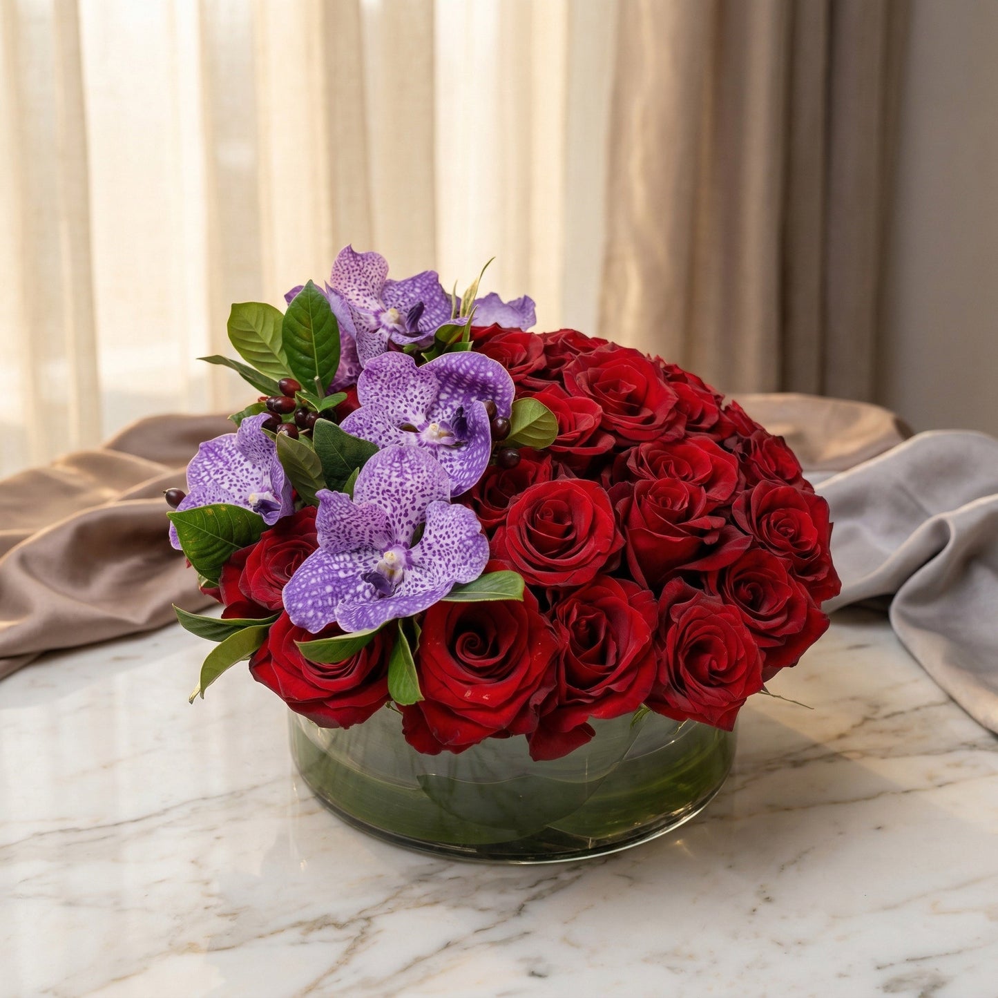 A low glass bowl filled with deep red roses and purple Vanda orchids - TJ Flowers NYC