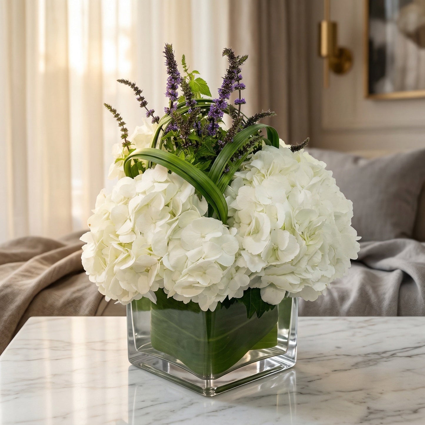 White hydrangeas and purple accents in a square glass vase with leaf wrap - TJ Flowers NYC