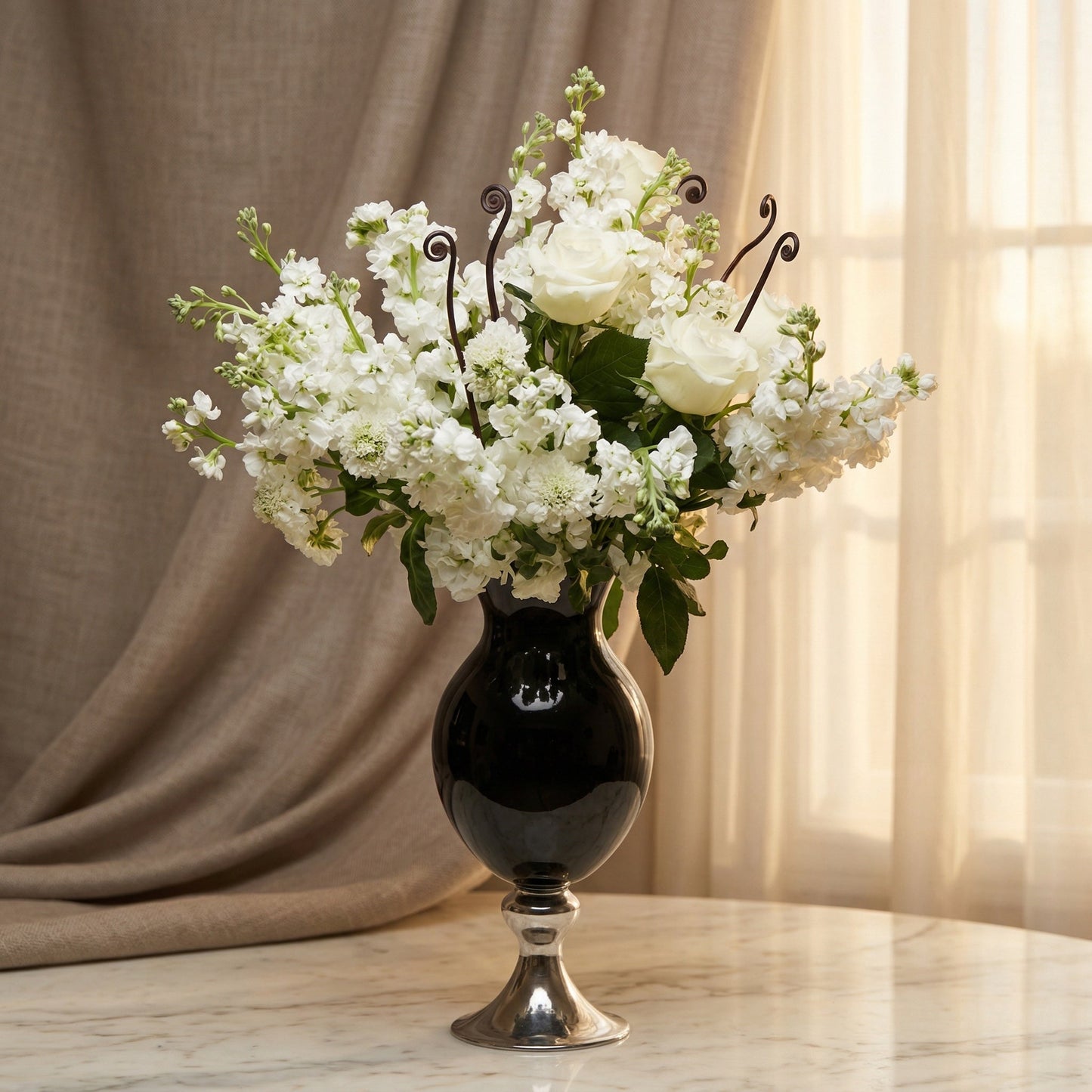Elegant white roses and stock flowers in a black and silver pedestal vase. - TJ Flowers NYC
