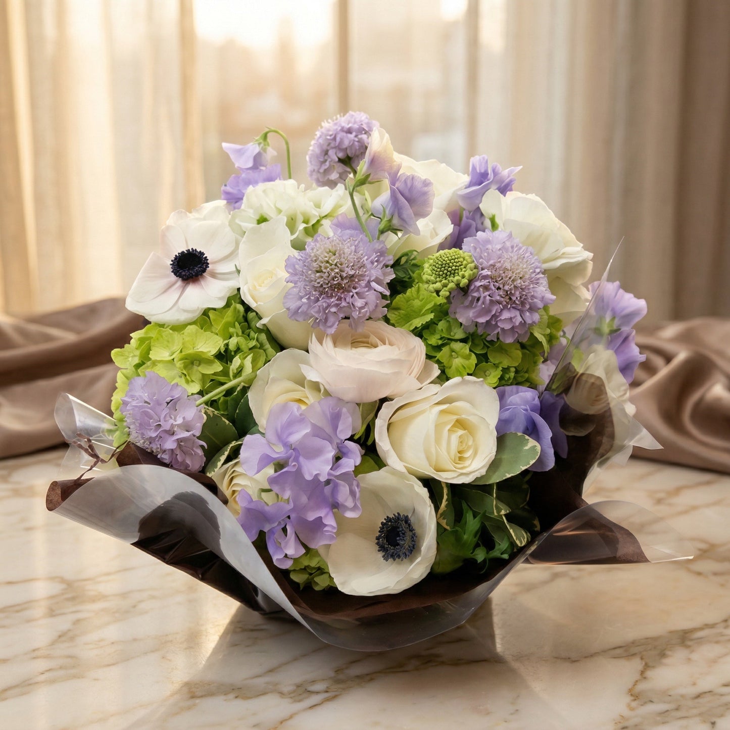 A bouquet of white roses, purple scabiosa, and green hydrangeas in a dark wrap - TJ Flowers NYC