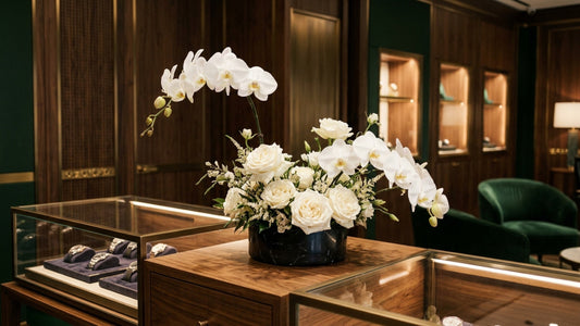 White orchid arrangement on a luxury watch boutique display counter, Madison Avenue — TJ Flowers NYC