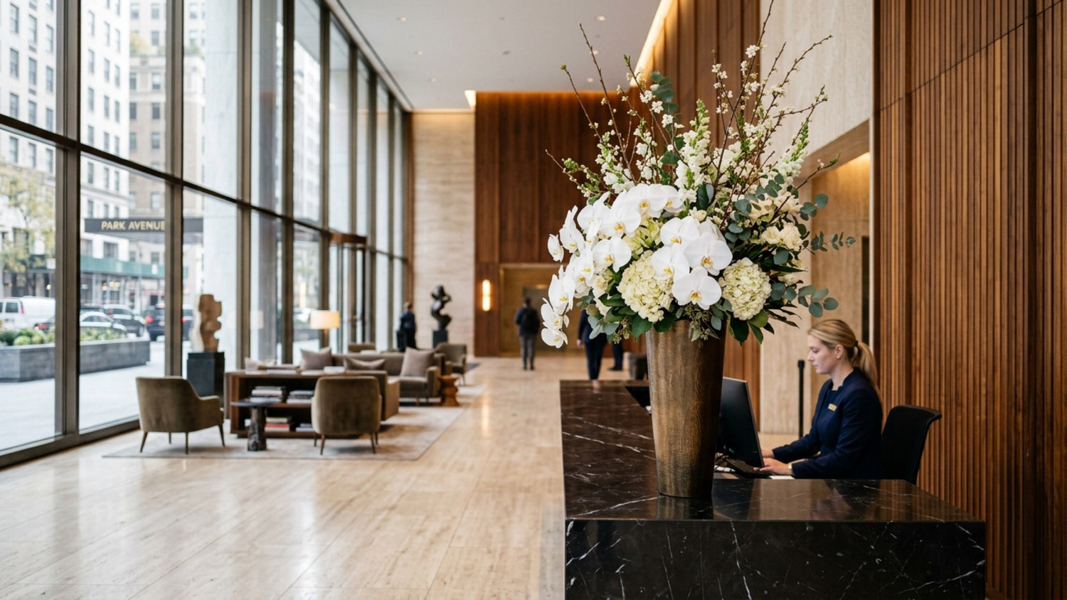 Statement orchid arrangement on a black marble reception desk in a Park Avenue corporate lobby — TJ Flowers NYC weekly corporate floral service