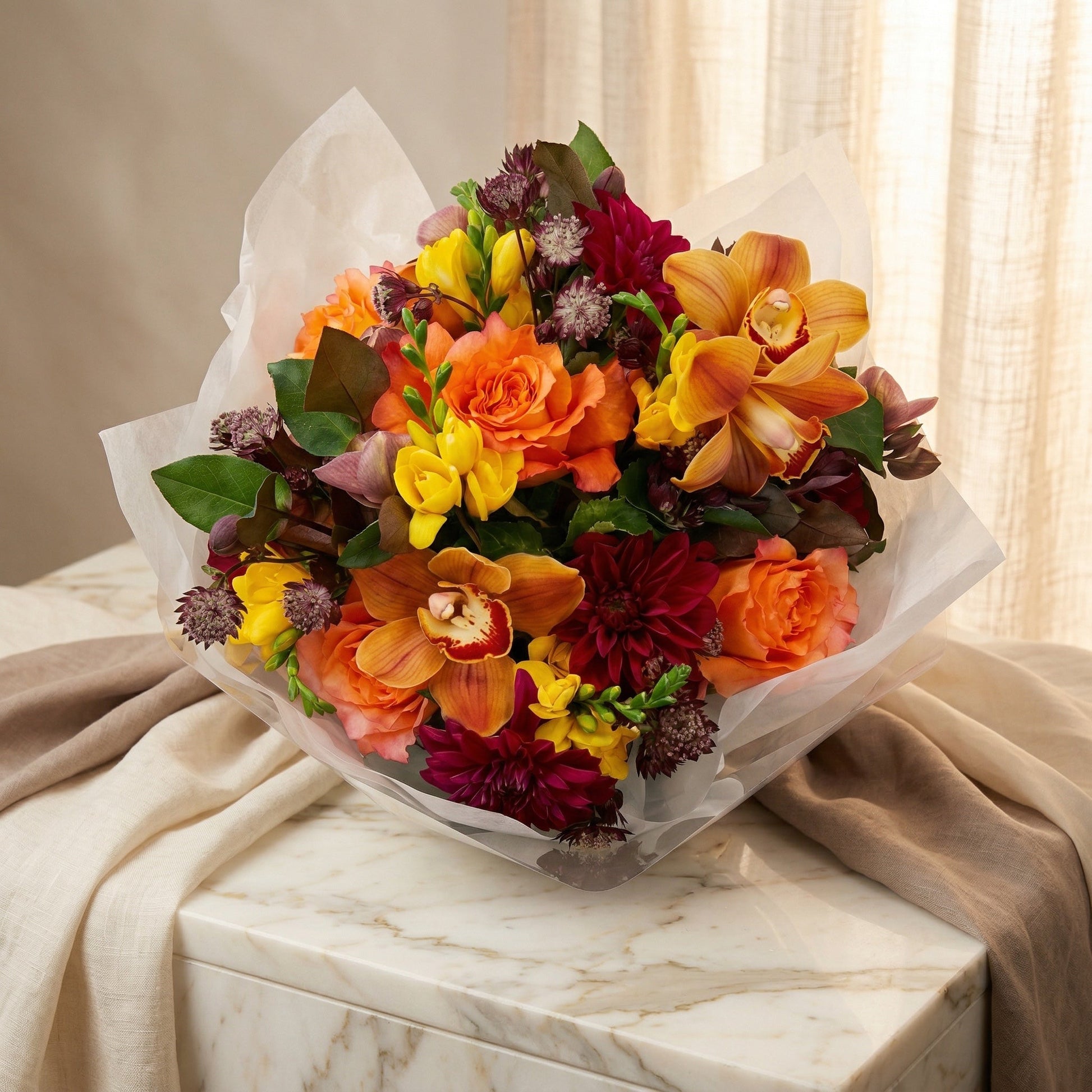 Vibrant bouquet with orange roses, yellow freesia, and orange cymbidium orchids in white wrap - TJ Flowers NYC