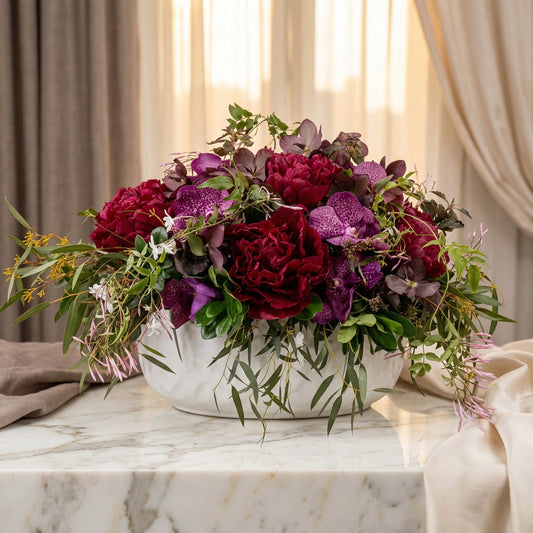 Deep red peonies and purple vanda orchids in a white textured bowl with greenery - TJ Flowers NYC