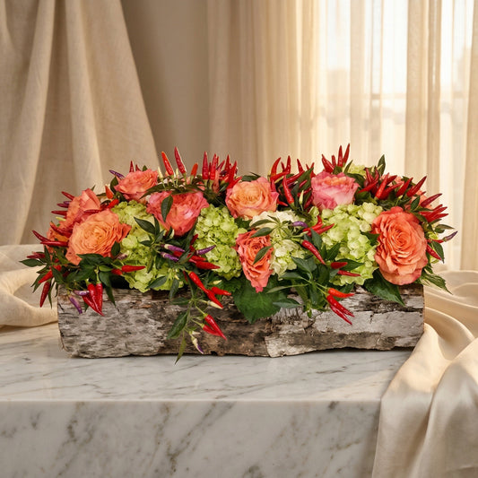 Coral roses and green hydrangeas with red chili peppers in a birch bark planter - TJ Flowers NYC