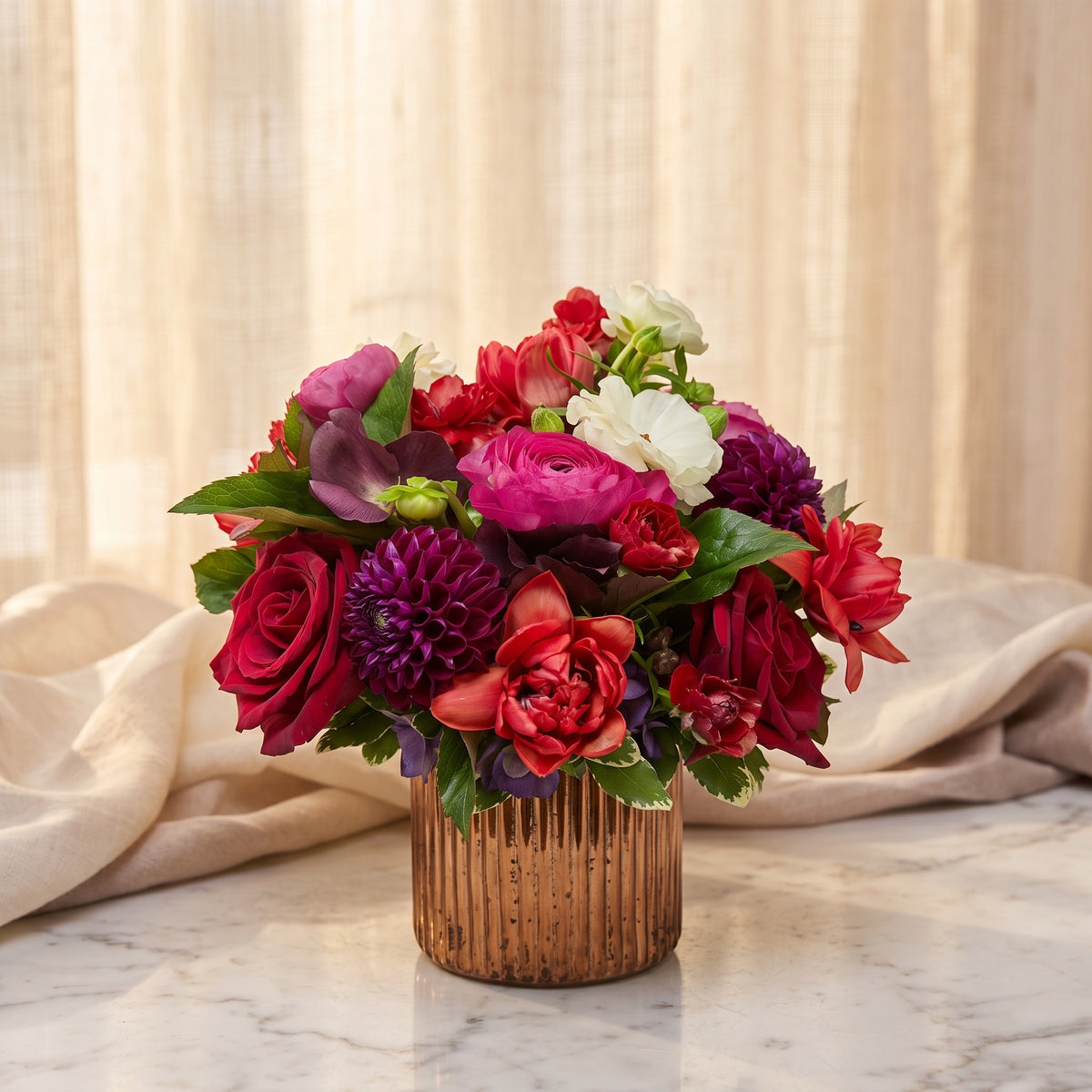 Red roses with hot pink ranunculus, plum dahlia and scarlet blooms in a fluted copper vase - TJ Flowers NYC