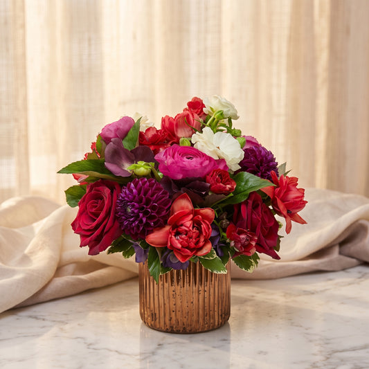 Red roses with hot pink ranunculus, plum dahlia and scarlet blooms in a fluted copper vase - TJ Flowers NYC