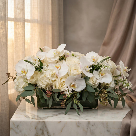 Elegant white phalaenopsis orchids, roses, and hydrangeas in a low glass vase with eucalyptus - TJ Flowers NYC