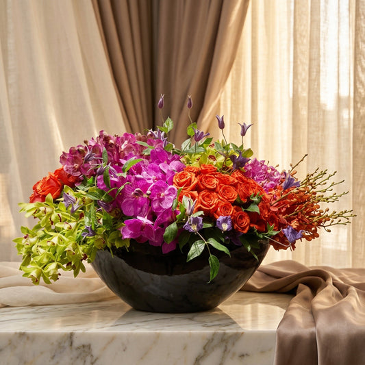 Vibrant purple and green orchids with orange roses in a black bowl - TJ Flowers NYC