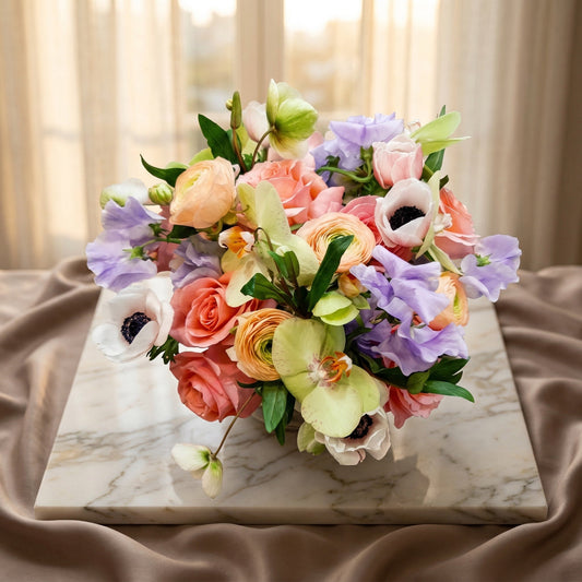 Pastel bouquet with roses, orchids, and sweet peas on a marble slab. - TJ Flowers NYC