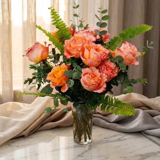 Peach and orange roses with eucalyptus and fern in a glass vase - TJ Flowers NYC