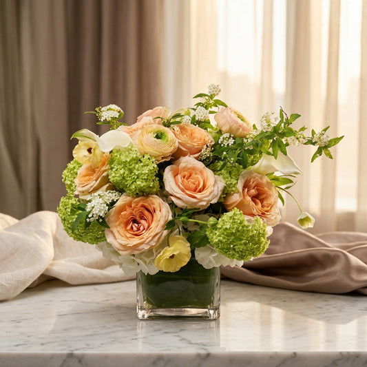 Peach roses and green hydrangeas in a square glass vase on a marble table - TJ Flowers NYC