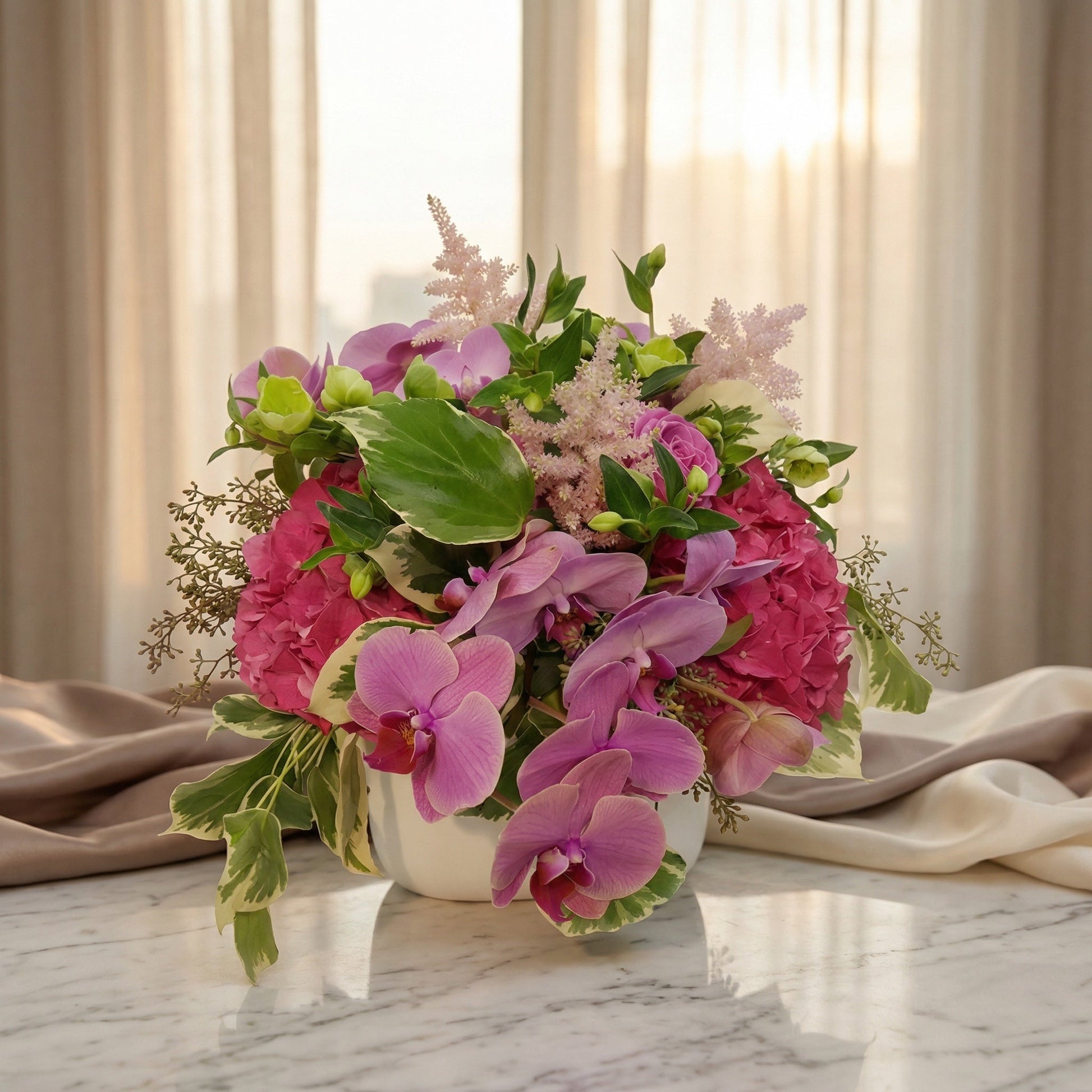Pink phalaenopsis orchids and fuchsia hydrangeas in a white vase on a marble table - TJ Flowers NYC