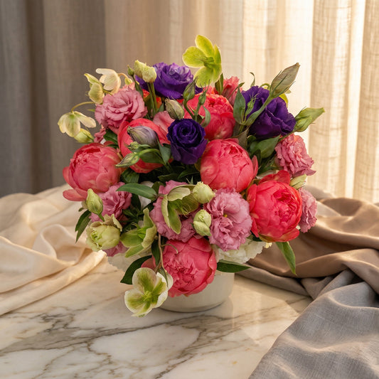 Vibrant bouquet with pink peonies, purple lisianthus, and green hellebores in a white vase - TJ Flowers NYC