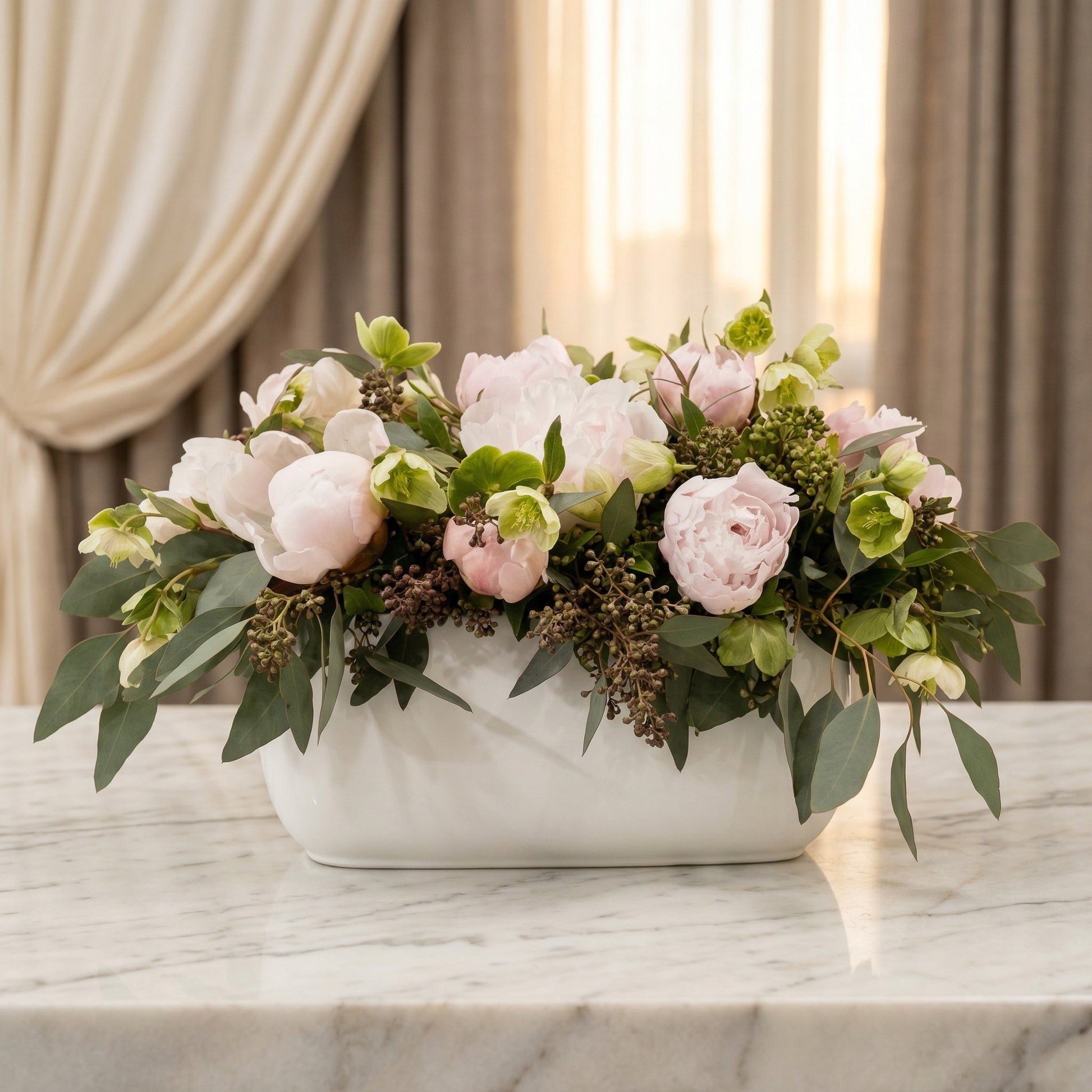 Blush pink peonies and green hellebores in a white ceramic vase on a marble table - TJ Flowers NYC