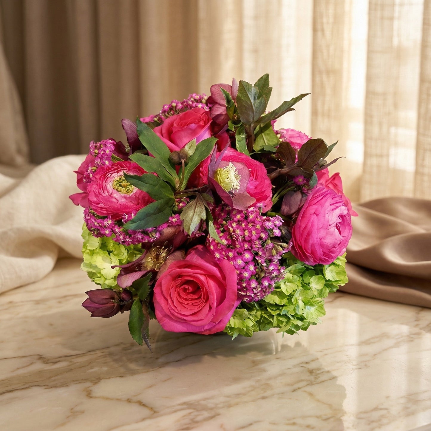Vibrant pink roses and ranunculus with green hydrangea in a low vase - TJ Flowers NYC