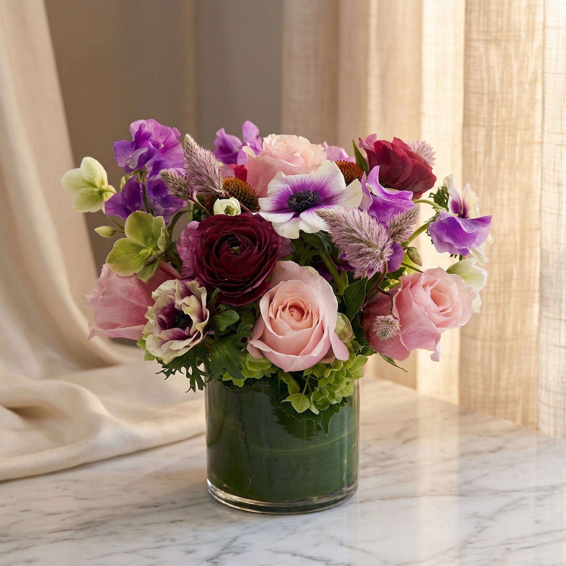 Purple and pink mixed bouquet with roses and anemones in a glass cylinder vase - TJ Flowers NYC