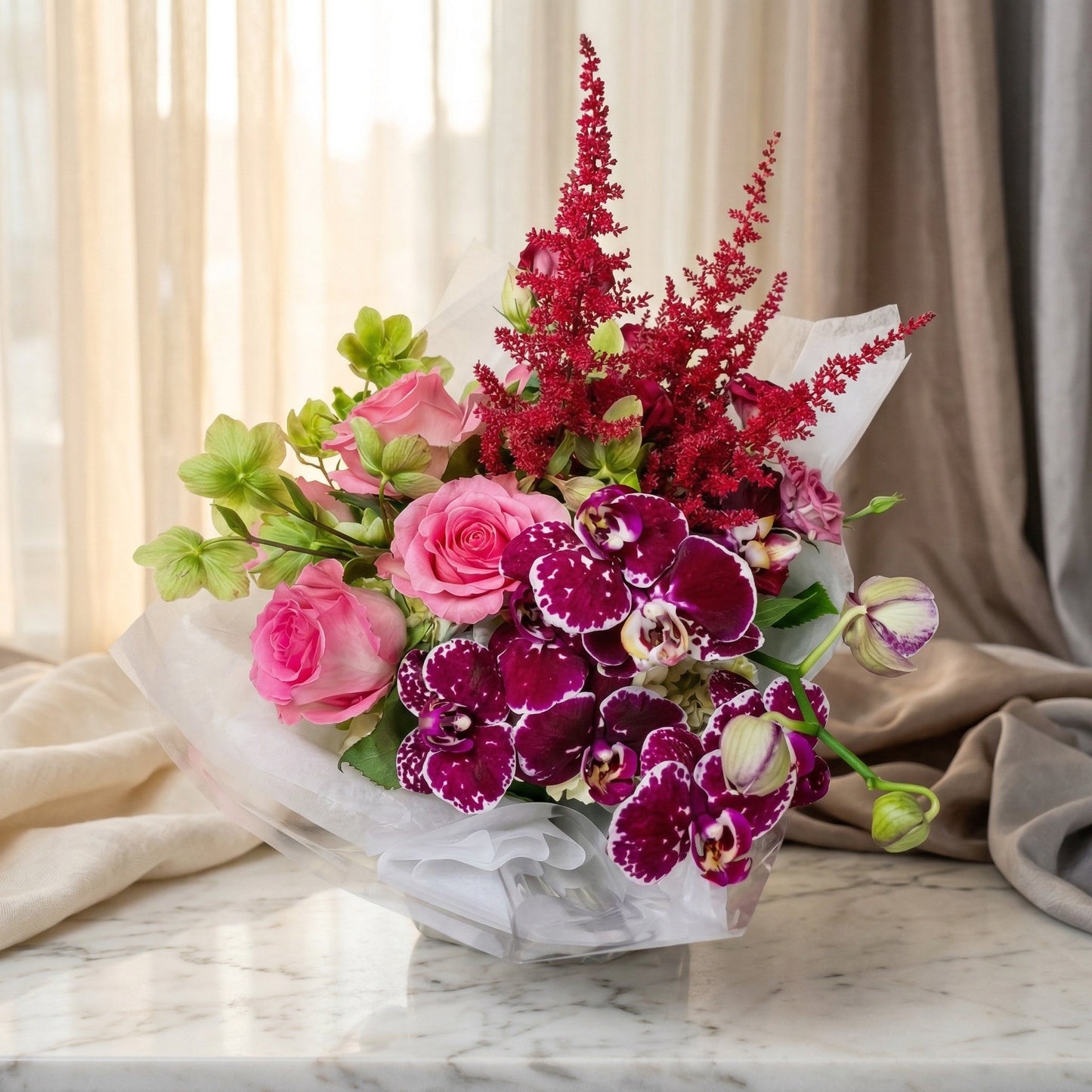 Pink roses, purple orchids, and red astilbe in a white paper-wrapped bouquet on a marble table - TJ Flowers NYC