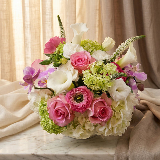 Pastel pink roses, purple orchids, and white hydrangeas in a low vase on marble - TJ Flowers NYC