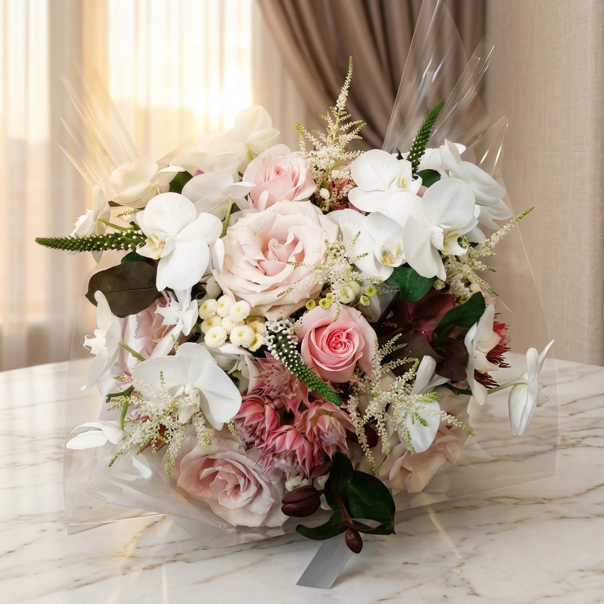 Pastel pink roses and white phalaenopsis orchids in a clear wrapped bouquet - TJ Flowers NYC