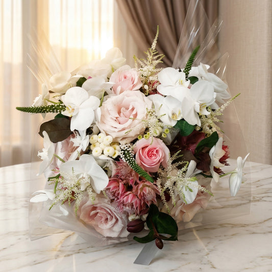 Pastel pink roses and white phalaenopsis orchids in a clear wrapped bouquet - TJ Flowers NYC