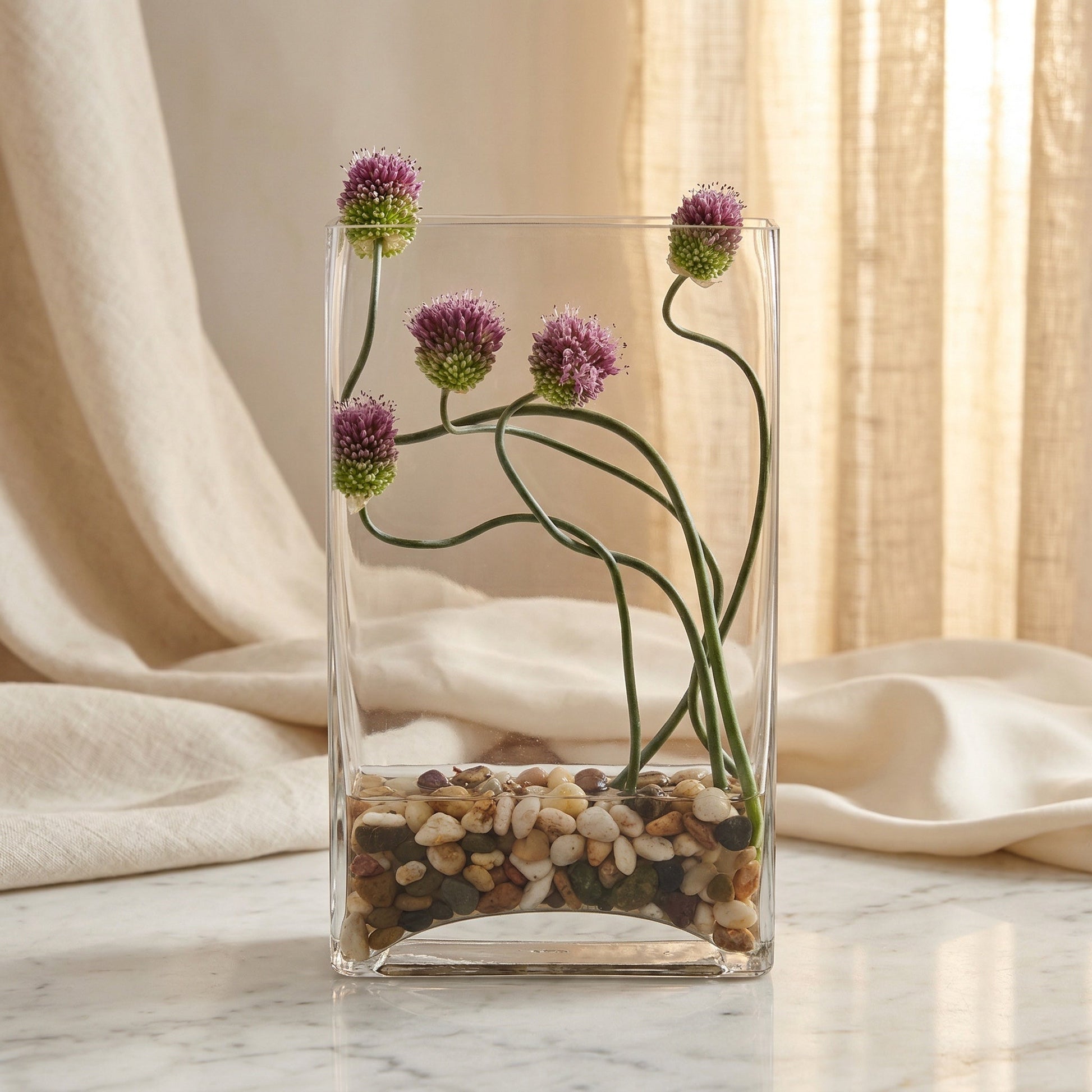 Purple allium flowers in a clear glass vase with river stones - TJ Flowers NYC