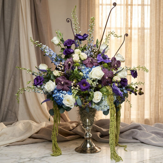 Purple orchids, blue hydrangeas, and white roses in a silver pedestal vase - TJ Flowers NYC