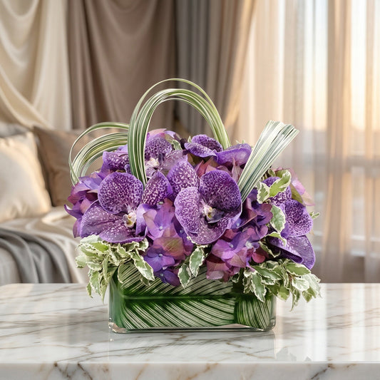 Purple Vanda orchids and hydrangeas in a modern glass vase with variegated leaves - TJ Flowers NYC