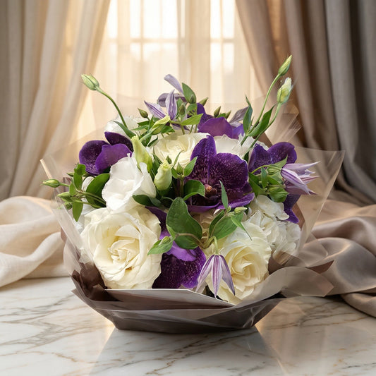 A bouquet of white roses and purple orchids wrapped in clear and brown film - TJ Flowers NYC