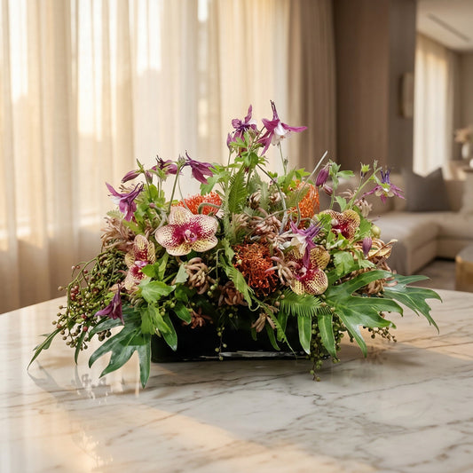 Modern arrangement with purple orchids, columbine, and orange pincushion protea in a black vase - TJ Flowers NYC
