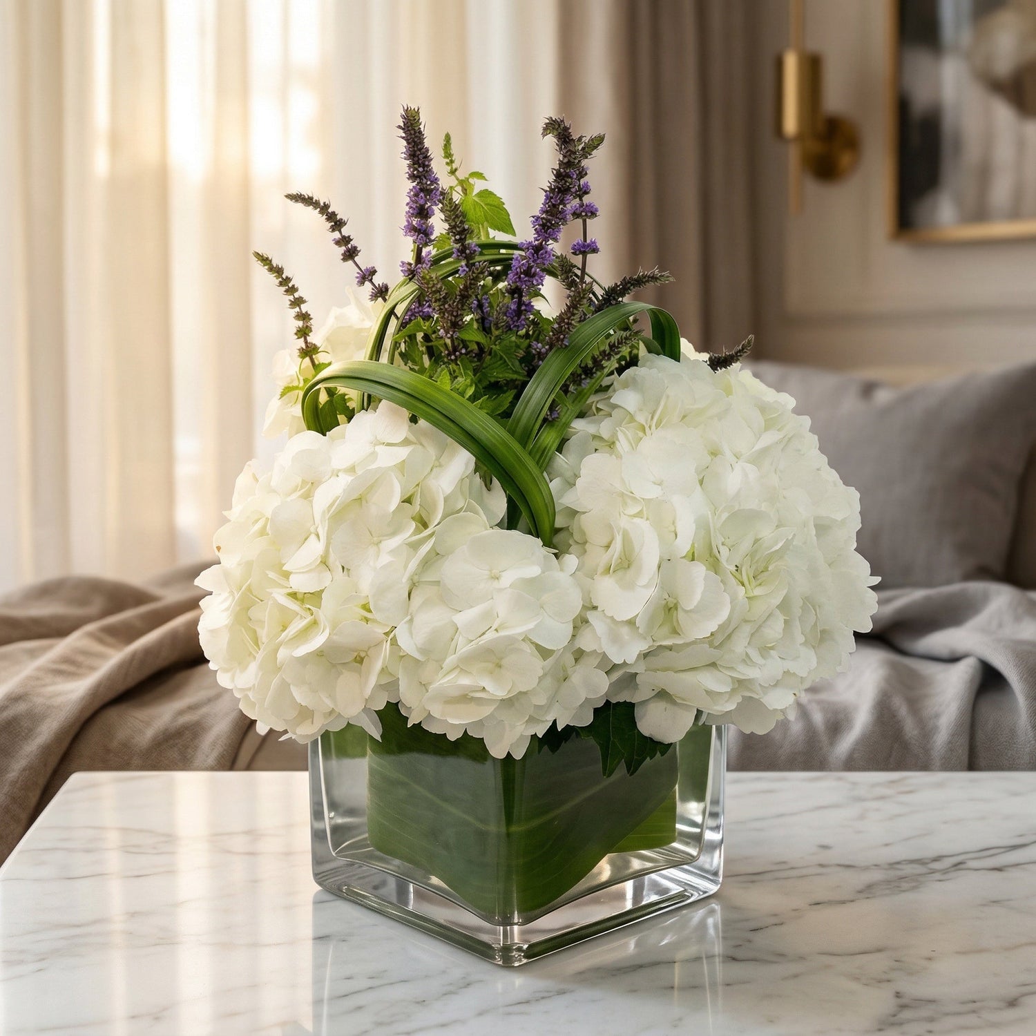 White hydrangeas and purple accents in a square glass vase with leaf wrap - TJ Flowers NYC