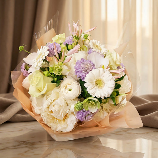 Pastel bouquet with white peonies, roses, orchids, and lavender scabiosa in peach wrap - TJ Flowers NYC