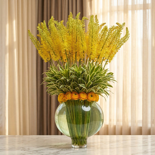 Tall yellow eremurus and orange ranunculus in a round glass vase - TJ Flowers NYC
