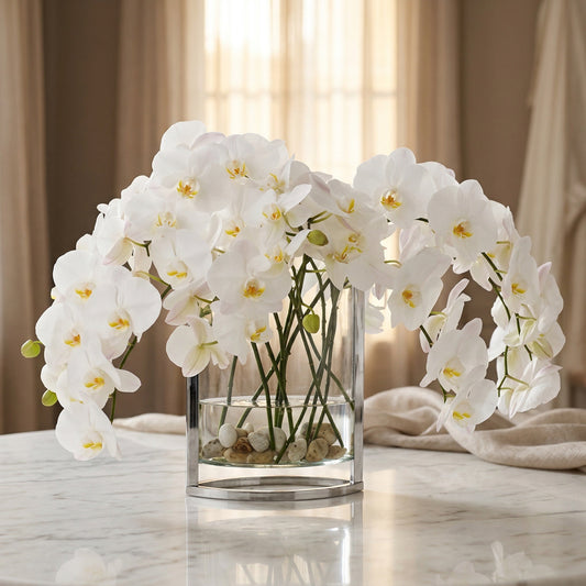 Elegant white phalaenopsis orchids in a modern glass and metal vase with river stones. - TJ Flowers NYC