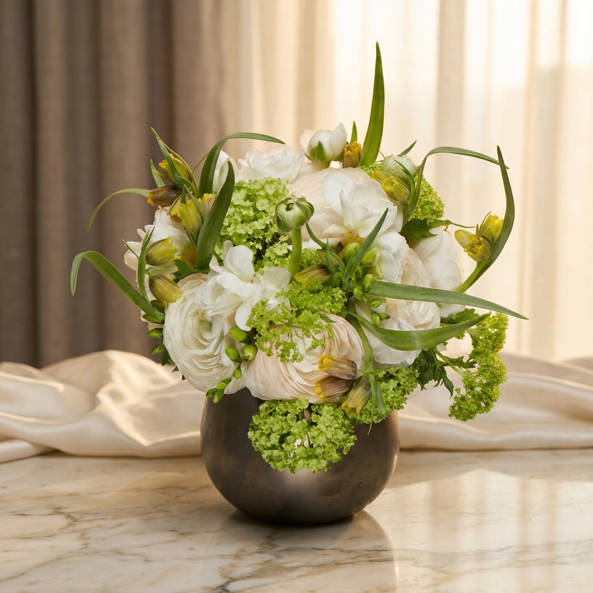White ranunculus and green viburnum in a dark metallic vase - TJ Flowers NYC