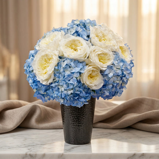 Blue hydrangeas and white garden roses in a dark textured vase on a marble table - TJ Flowers NYC