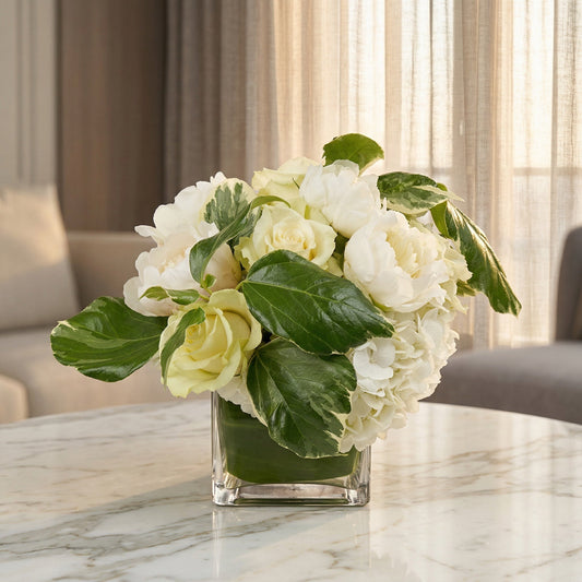 White roses, peonies, and hydrangeas in a square glass vase with variegated leaves - TJ Flowers NYC