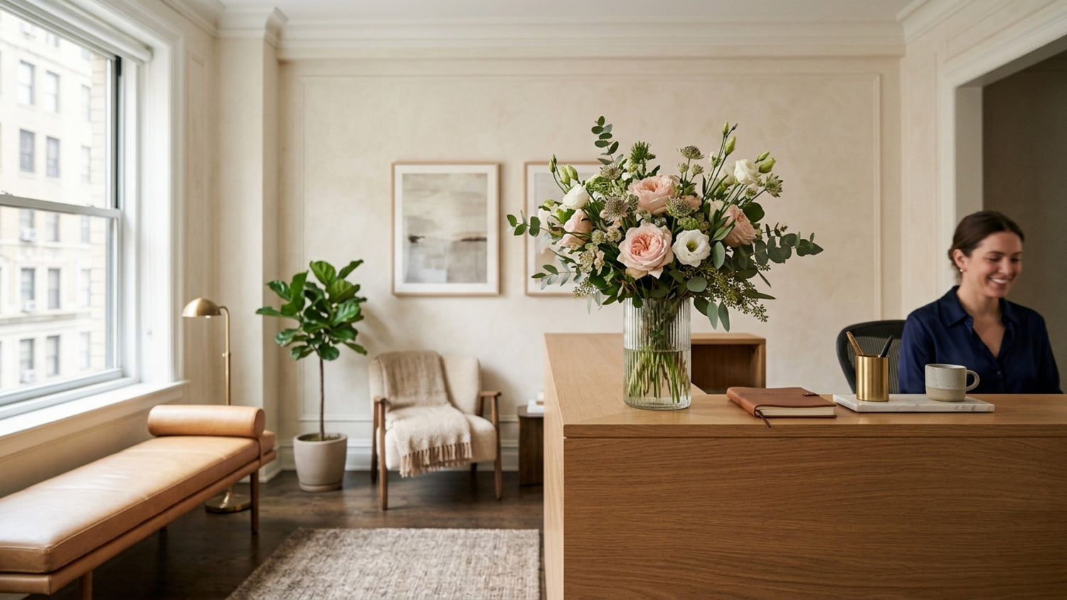 Weekly reception arrangement of blush garden roses in a ribbed glass vase on an Upper East Side office reception desk — TJ Flowers NYC office flower subscription